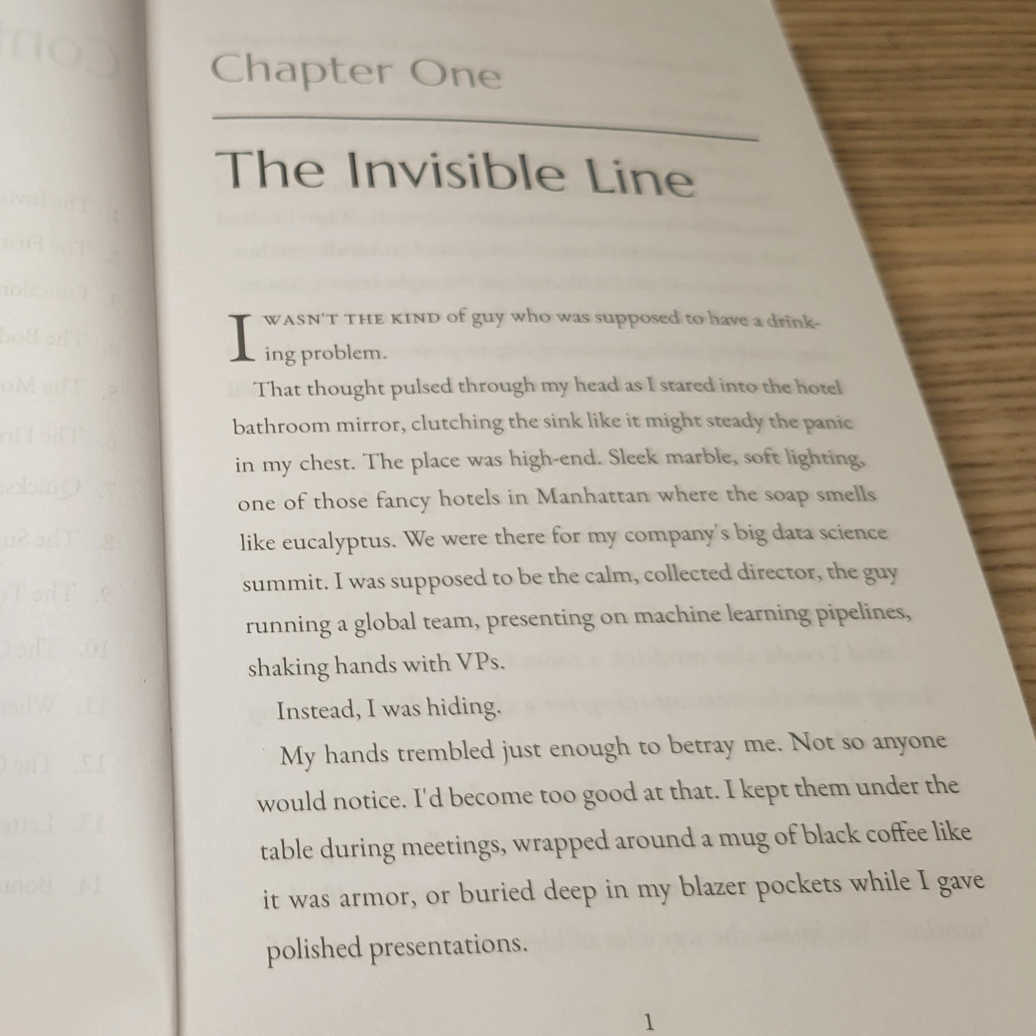 Open book with text beginning 'The Invisible Line' on a wooden surface
