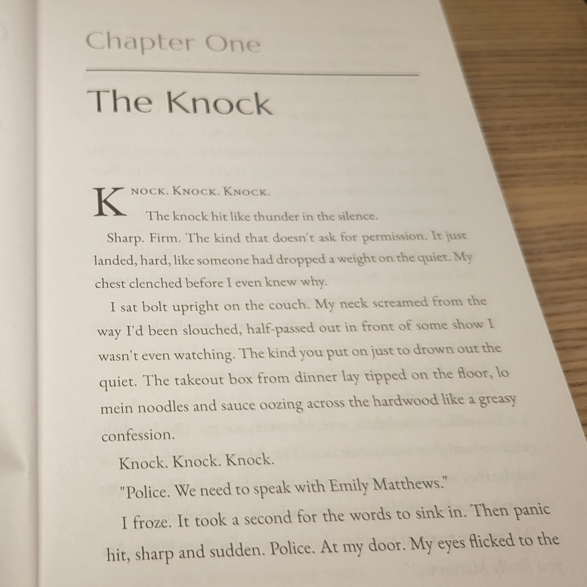 Book page with text titled 'The Knock' on a wooden surface